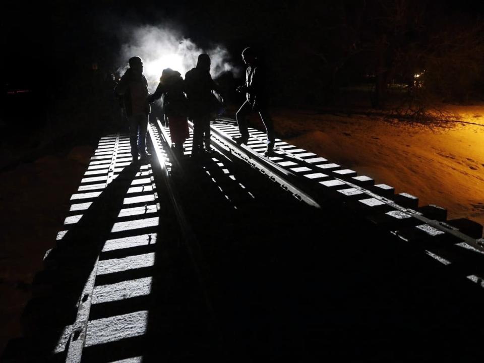 According to numbers from Immigration, Refugees and Citizenship Canada, there were&#xa0;110,661 refugee applications &#x002014; 38,681 government-assisted and 71,980 privately sponsored refugees &#x002014; yet to be processed as of April 26. In this file photo, eight migrants from Somalia cross into Canada illegally from the United States by walking down this train track.  (John Woods/Canadian Press - image credit)