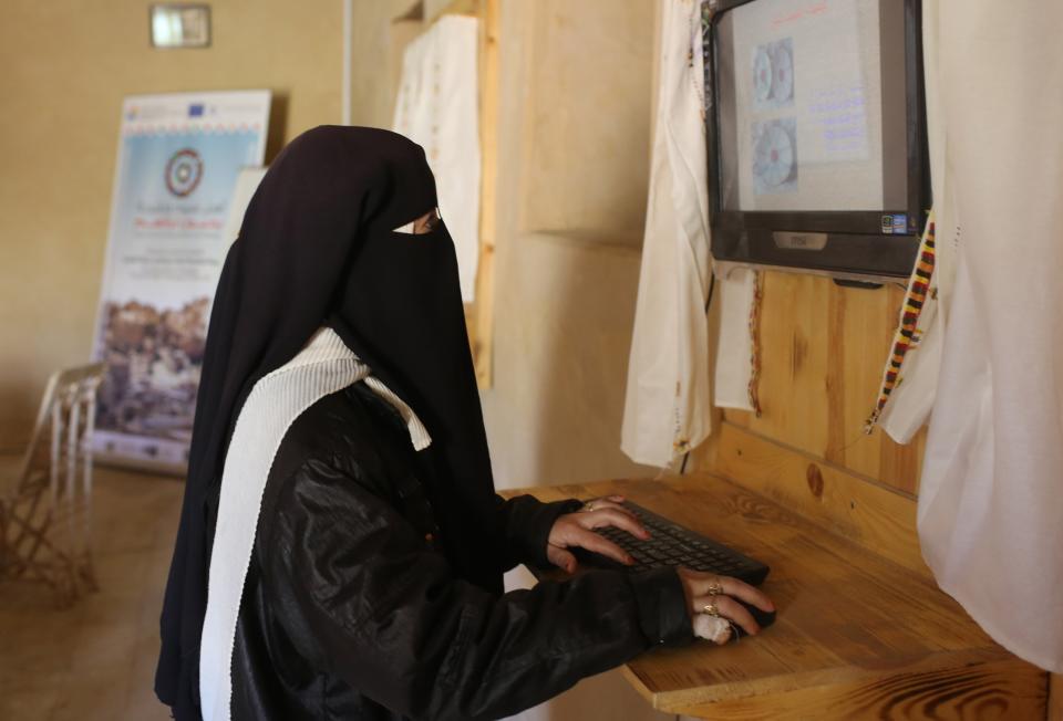 A girl types on a computer where she works at the Centre for Reinforcing Cultural Heritage, in Siwa