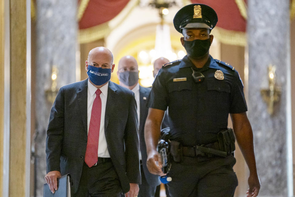 Postmaster General Louis DeJoy, left, is escorted to House Speaker Nancy Pelosi's office on Capitol Hill in Washington, Wednesday, Aug. 5, 2020. Some clarity is beginning to emerge from the bipartisan Washington talks on a huge COVID-19 response bill. An exchange of offers and meeting devoted to the Postal Service on Wednesday indicates the White House is moving slightly in House Speaker Nancy Pelosi's direction on issues like aid to states and local governments and unemployment insurance benefits. But the negotiations have a long ways to go. (AP Photo/Carolyn Kaster)