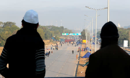 Supporters of the Tehrik-e-Labaik Pakistan Islamist political party watch as a crane removes a container blocking the highway to Islamabad from their protest site at Faizabad junction in Islamabad, Pakistan November 27, 2017. REUTERS/Caren Firouz