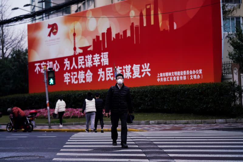 A man wearing a face mask walks across a road as the country is hit by an outbreak of the novel coronavirus COVID-19, in Shanghai