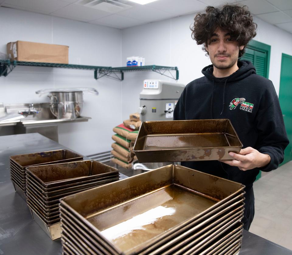 Jet's Pizza assistant manager Joshaua Bastajian shows off the secret to making their pizza so different - a special pan - during a first look inside the new pizza chain on Wednesday, Dec. 13, 2024. Jet's is scheduled to open in Pensacola in early January 2024.
