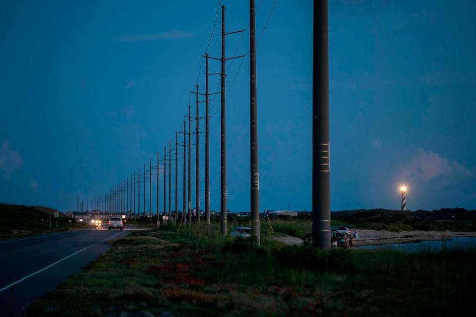 The Cape Hatteras Lighthouse illuminates the evening sky at dusk as traffic moves along NC 12 north of Buxton, N.C. on Tuesday, June 29, 2021.