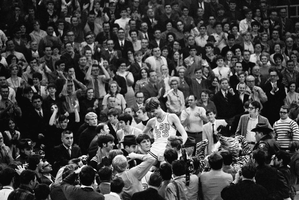 THIS CORRECTS THE DATE TO JAN. 31, 1970, NOT JAN. 28, 1979, AS ORIGINALLY SENT - - FILE - Pete Maravich (23) gets a boost from players and fans after he broke the all-time scoring record in Baton Rouge, La., Jan. 31, 1970. Calmly looking on at far left center is Pete's dad, Press, who coaches the Louisiana State Tigers. Those who played with, followed or knew the late Maravich are conflicted about the seemingly inevitable moment — likely this Sunday — when he could be supplanted by Iowa women's basketball sensation Caitlin Clark atop the NCAA's all-time scoring list. (AP Photo/File)
