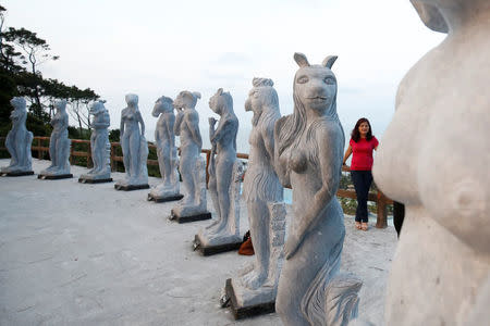 A woman stands near godlike sculptures with animal heads and human genitalia at Hon Dau resort in Hai Phong city, east of Hanoi, Vietnam April 5, 2018. Picture taken April 5, 2018. REUTERS/Kham