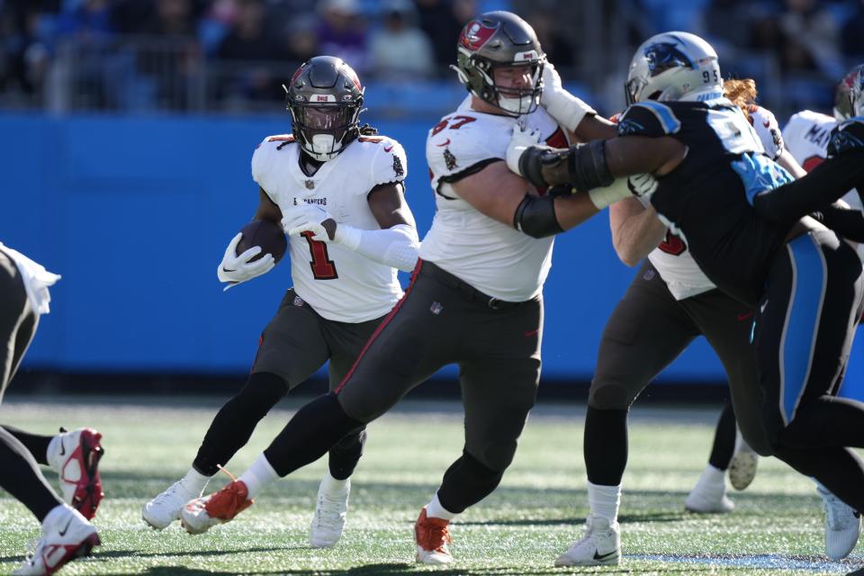 Jan 7, 2024; Charlotte, North Carolina, USA; Tampa Bay Buccaneers running back Rachaad White (1) follows the block by offensive tackle Luke Goedeke (67) during the second quarter against the Carolina Panthers at Bank of America Stadium. Mandatory Credit: Jim Dedmon-USA TODAY Sports