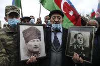 CORRECTING IDENTY OF PORTRAITS TO TURKEY’S FOUNDER MUSTAFA KEMAL ATATURK, LEFT, AND AZERBAIJAN’S LATE PRESIDENT HAYDAR ALIYEV, RIGHT - An Azerbaijani man holds portraits of Turkey’s founder Mustafa Kemal Ataturk, left, and Azerbaijan’s late president Haydar Aliyev, father of Ilham Aliyev wearing in KGB Gen. Major uniform on the right, as he celebrates the transfer of the Lachin region to Azerbaijan's control, as part of a peace deal that required Armenian forces to cede the Azerbaijani territories they held outside Nagorno-Karabakh, in Aghjabadi, Azerbaijan, Tuesday, Dec. 1, 2020. Azerbaijan has completed the return of territory ceded by Armenia under a Russia-brokered peace deal that ended six weeks of fierce fighting over Nagorno-Karabakh. Azerbaijani President Ilham Aliyev hailed the restoration of control over the Lachin region and other territories as a historic achievement. (AP Photo/Emrah Gurel)