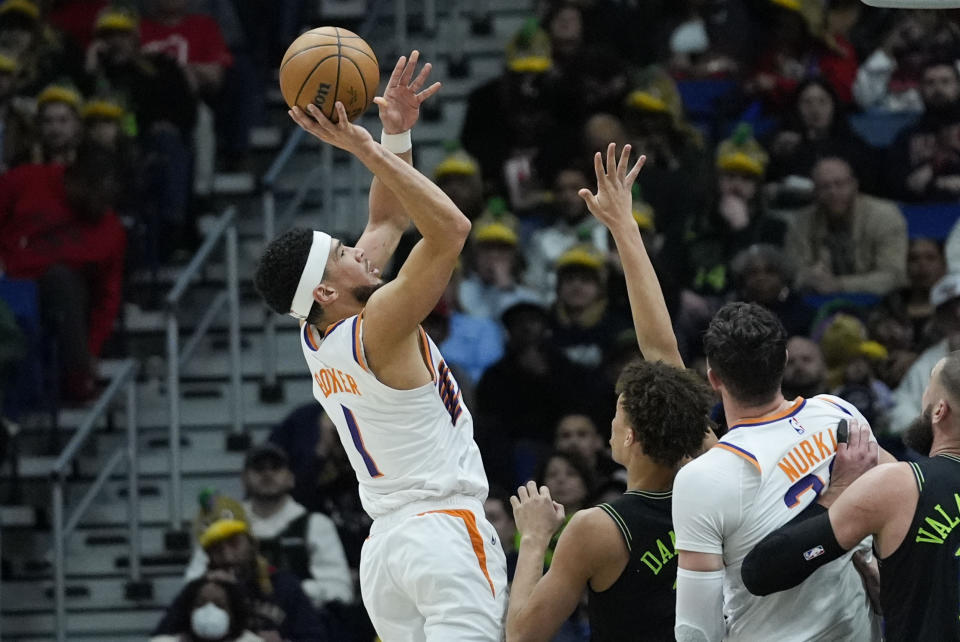 Phoenix Suns guard Devin Booker (1) shoots against New Orleans Pelicans guard Dyson Daniels, second from left, in the first half of an NBA basketball game in New Orleans, Friday, Jan. 19, 2024. (AP Photo/Gerald Herbert)