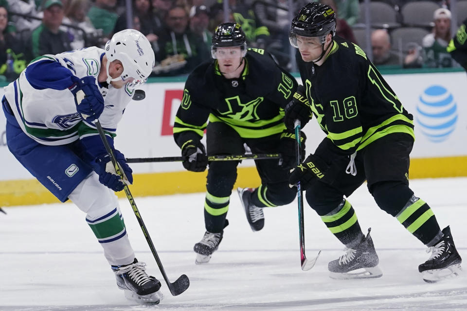 Vancouver Canucks center Elias Pettersson (40) skates for the puck against Dallas Stars centers Max Domi (18) and Ty Dellandrea (10) during the first period of an NHL hockey game in Dallas, Saturday, March 25, 2023. (AP Photo/LM Otero)