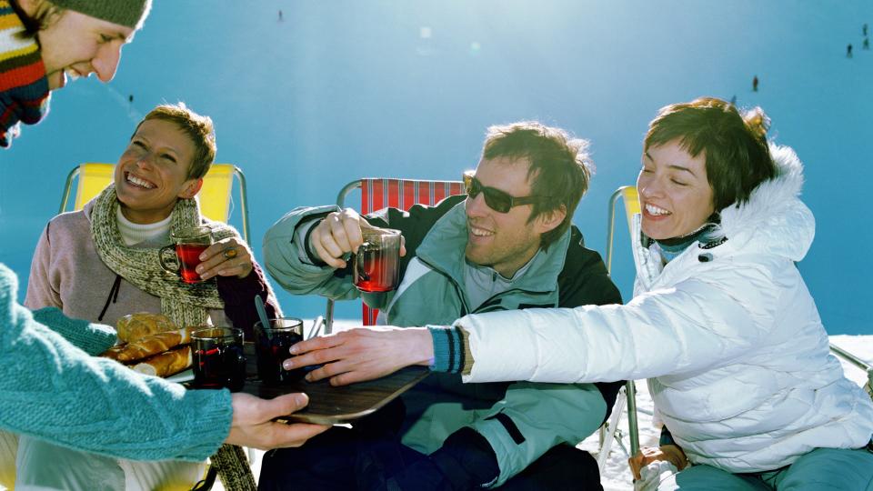 Man holding tray of bread and drinks for three friends