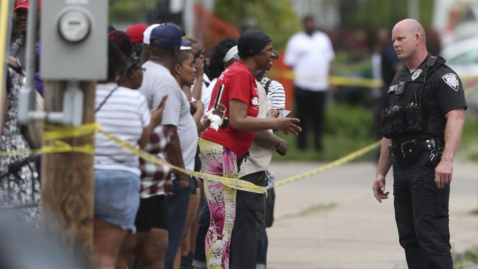 Police speak to bystanders while investigating after a shooting at a supermarket on Saturday, May 14, 2022, in Buffalo, N.Y.  Officials said the gunman entered the supermarket with a rifle and opened fire. Investigators believe the man may have been livestreaming the shooting and were looking into whether he had posted a manifesto online.