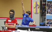 Amid concerns of the spread of COVID-19, Aiden Trabucco, right, wears a mask as he raises his hand to answer a question behind Anthony Gonzales during a summer STEM camp at Wylie High School Tuesday, July 14, 2020, in Wylie, Texas. (AP Photo/LM Otero)