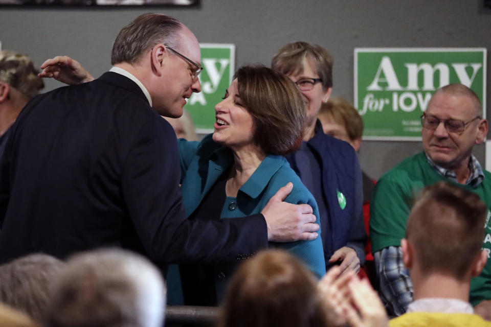 FILE - In this Feb. 1, 2020 file photo Democratic presidential candidate Sen. Amy Klobuchar, D-Minn., center, gets a kiss from husband John Bessler, upon arriving at a rally in Sioux City, Iowa. Sen. Klobuchar announced Monday, March 23 that her husband has tested positive for the coronavirus.(AP Photo/Gene J. Puskar File)