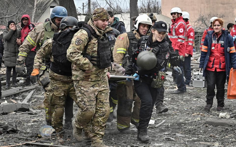Soldiers and policemen carry a local resident on a stretcher at the site of a Russian missile strike in Zaporizhzhia
