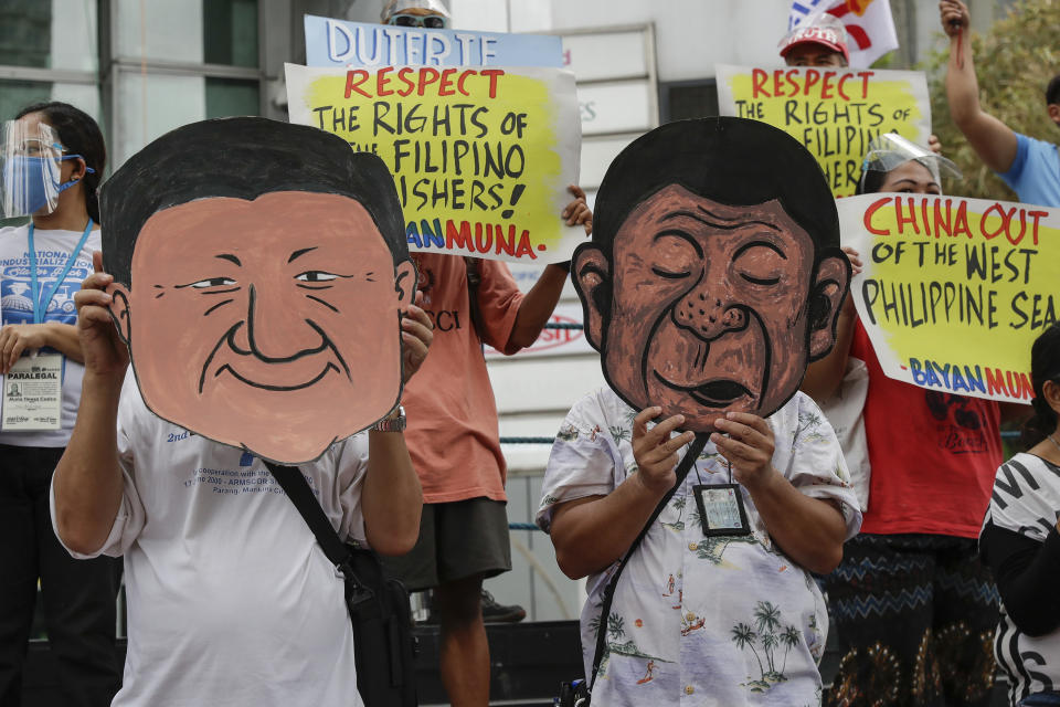 FILE - Protesters wear a mask of Philippine President Rodrigo Duterte, right, and Chinese President Xi Jinping during a rally outside the Chinese consulate in Manila, Philippines on May 7, 2021. The Philippine military defiantly redeployed two supply boats on Monday, Nov. 22, 2021 to provide food to Filipino marines guarding a disputed shoal in the South China Sea after the Chinese coast guard used water cannons to forcibly turn the boats away in an assault last week that drew angry condemnation and warnings from Manila. (AP Photo/Aaron Favila, File)