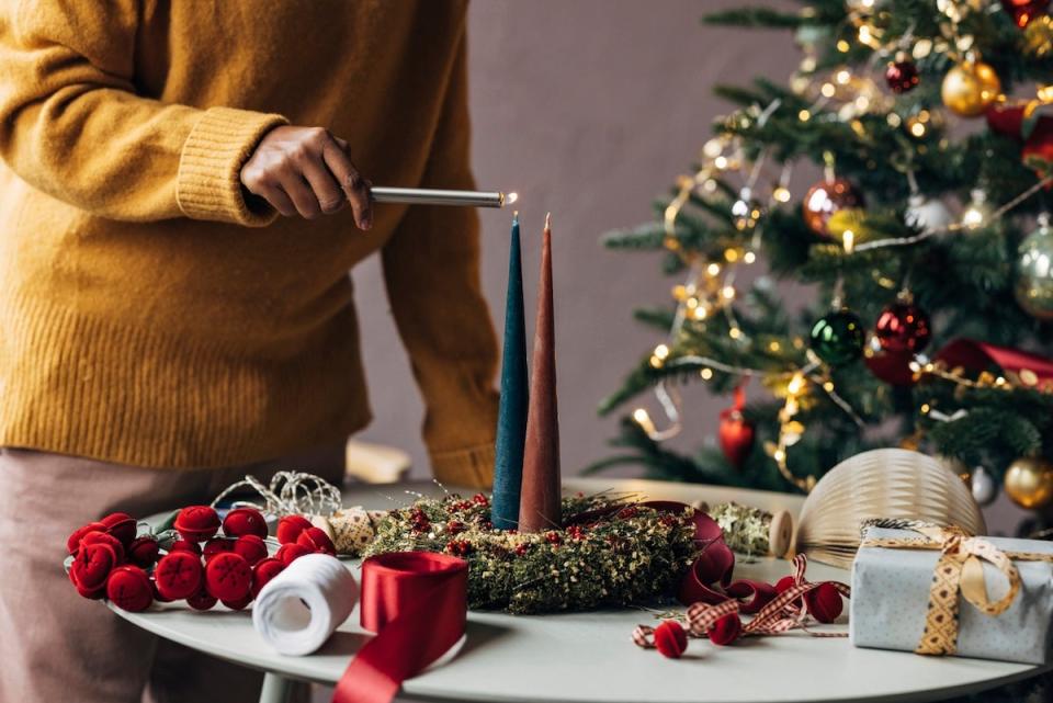 A person lighting a candle using a long candle lighter for candle safety.