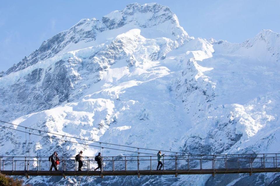Hikers walk through a swing bridge in the Hooker Valley track at in the South Island, New Zealand.