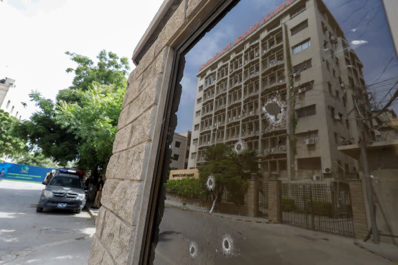 The Pakistan Stock Exchange building is reflected in the bullet riddled window of the security check post after an attack in Karachi