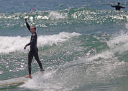 OCEANSIDE, CA - MAY 6: A Surfer waves a flower lei during a "paddle-out" in honor of NFL star Junior Seau on May 6, 2012 in Oceanside, California. Seau, who played for various NFL teams including the San Diego Chargers, Miami Dolphins and New England Patriots was found dead in his home on May 2nd of an apparent suicide. Family members have decided to donate his brain for research on links between concussions and possible depression. (Photo by Sandy Huffaker/Getty Images)