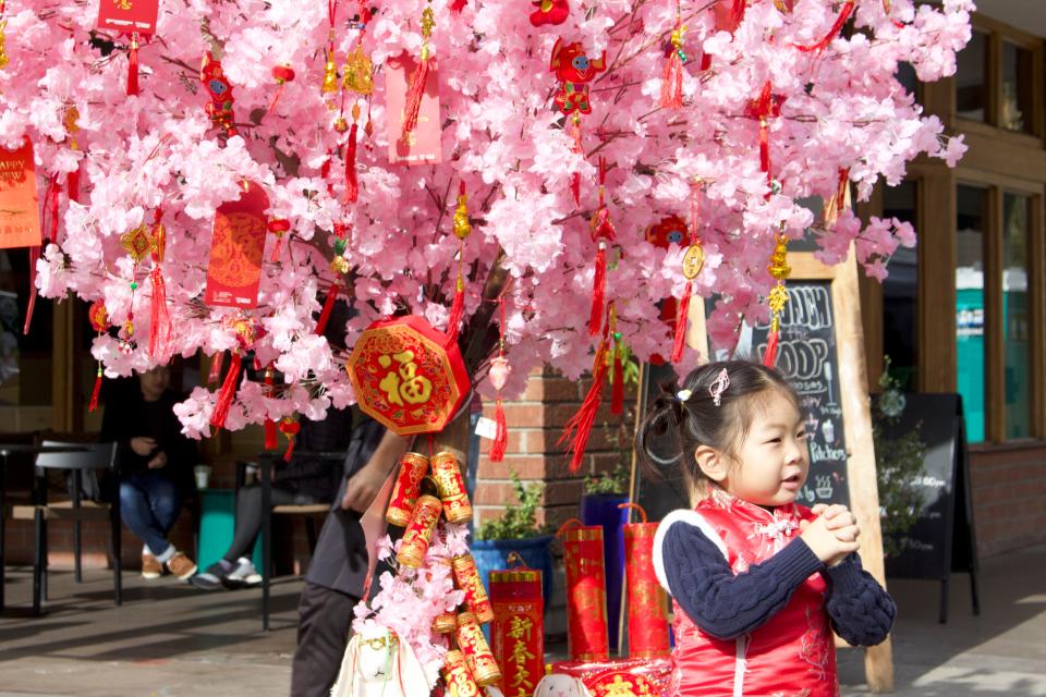 A child takes a picture near decorations set up for the city of Alhambra's Lunar New Year Festival on Jan. 29, 2023.