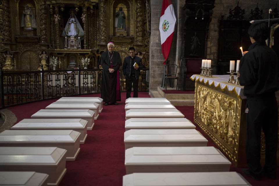 En imagen del 14 de agosto de 2018, el obispo de Ayacucho, Salvador José Miguel Piñeiro, izquierda, permanece de pie junto a un asistente detrás de los ataúdes de aldeanos que murieron a manos de las guerrillas del grupo Sendero Luminoso y el ejército peruano en la década de 1980, en la Catedral de Ayacucho, Perú. Más de 20.300 peruanos aún tienen la condición de desaparecidos tras la violencia entre las fuerzas de seguridad y los ultraizquierdistas de Sendero Luminoso en las décadas de 1980 y 1990. (AP Foto/Rodrigo Abd)