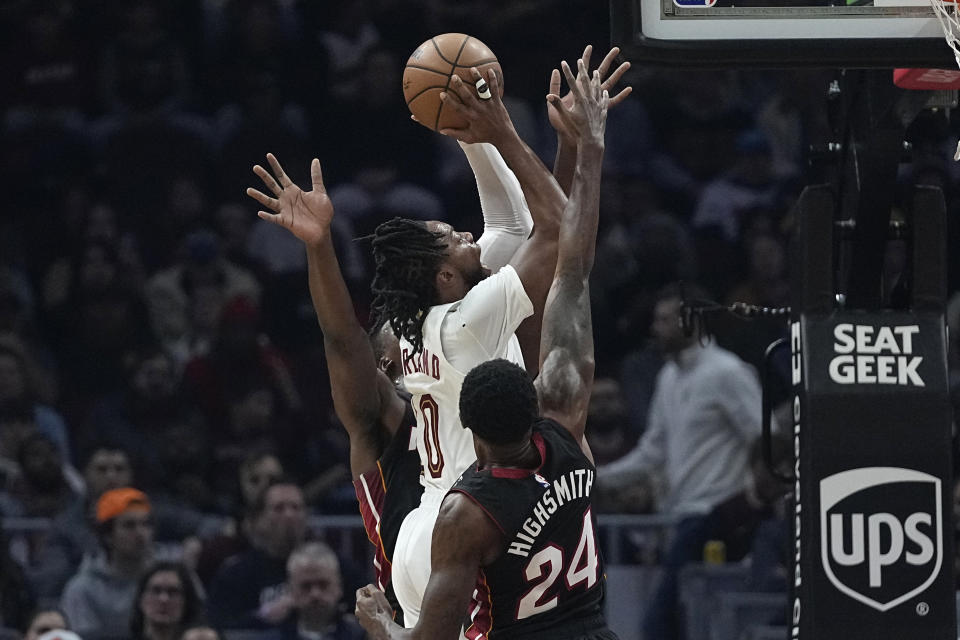 Cleveland Cavaliers guard Darius Garland (10) shoots between Miami Heat center Thomas Bryant, rear, and forward Haywood Highsmith (24) during the first half of an NBA basketball game Wednesday, Nov. 22, 2023, in Cleveland. (AP Photo/Sue Ogrocki)