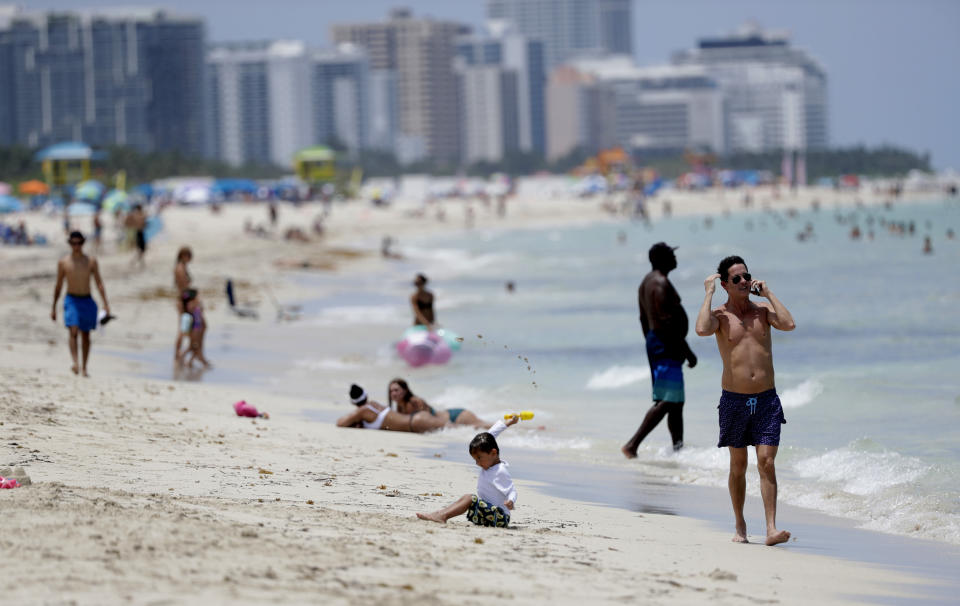 Beach goers walk along the shore on Miami Beach, Florida's famed South Beach, Tuesday, July 7, 2020. Beaches in Miami-Dade County reopened Tuesday after being closed July 3 through 6 to prevent the spread of the new coronavirus. (AP Photo/Wilfredo Lee)