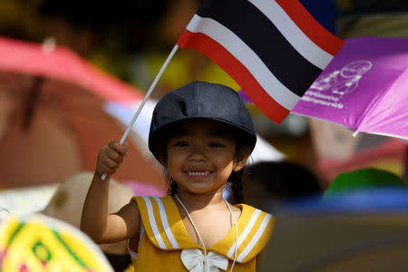 A child holds a Thai flag as people wait for a coronation procession for Thailand's newly crowned King Maha Vajiralongkorn in Bangkok, Thailand May 5, 2019. REUTERS/Chalinee Thirasupa