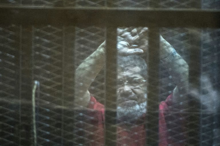 Egypt's ousted Islamist president Mohamed Morsi gestures from behind bars during his trial at the police academy in Cairo