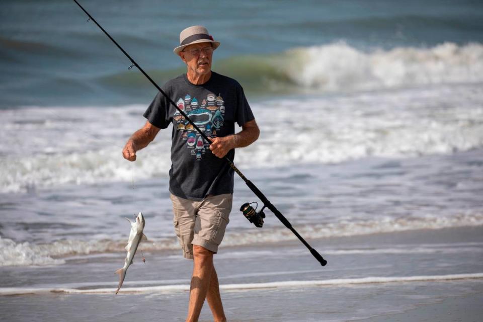 Mike Stranak returns from the surf with a small shark at a surf fishing clinic held by The South Carolina Department of Natural Resources at Huntington Beach State Park on Thursday. July 14, 2022.