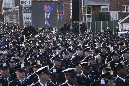 Law enforcement officers turn their backs on a live video monitor showing New York City Mayor Bill de Blasio as he speaks at the funeral of slain New York Police Department (NYPD) officer Rafael Ramos near Christ Tabernacle Church in the Queens borough of New York December 27, 2014. REUTERS/Shannon Stapleton
