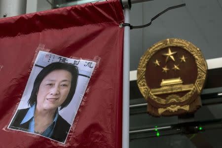 A portrait of Chinese journalist Gao Yu is displayed by a protester in front of the national emblem of China during a demonstration calling for the release of Gao, Hong Kong publisher Yao Wentian and Chinese lawyer Pu Zhiqiang, outside the Chinese liaison office in Hong Kong May 11, 2014. REUTERS/Tyrone Siu