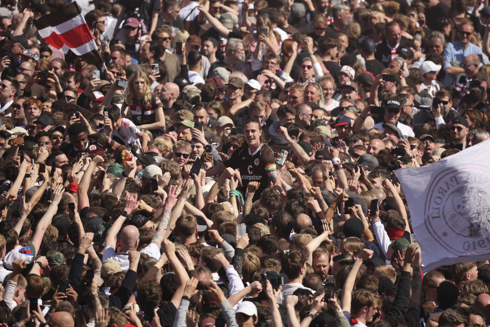 St. Pauli's Jackson Irvine, center, celebrates with fans who invaded the field after their team won 3-1 during a second division, Bundesliga soccer match between St. Pauli and VfL Osnabrück, at the Millerntor Stadium, in Hamburg, Germany, Sunday, May 12, 2024. (Christian Charisius/dpa via AP)