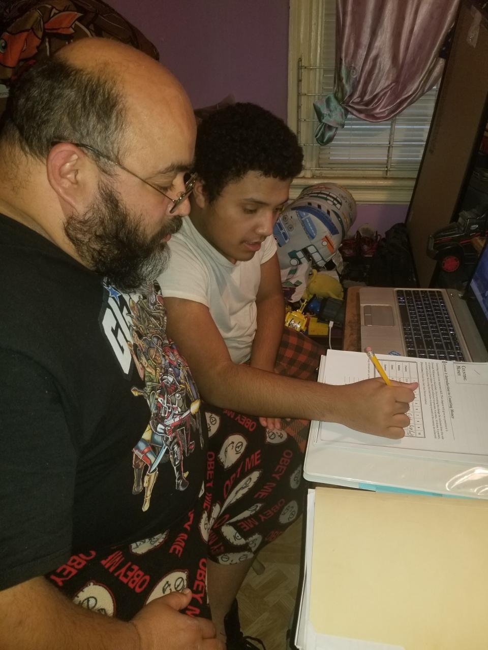 William Martinez helps his son, Angel, 13, with remote learning. April 9, 2020.