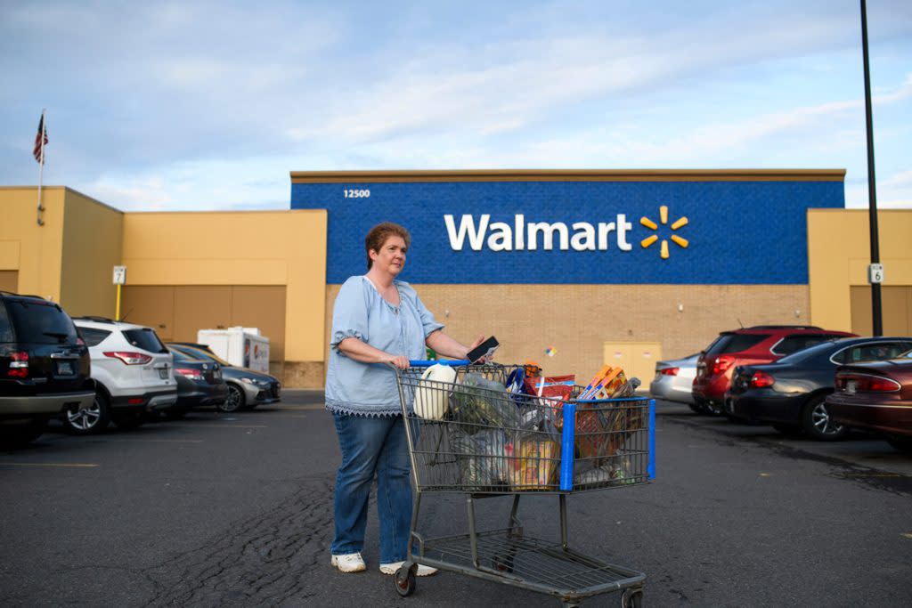 A woman leaves Walmart with groceries in her shopping cart.