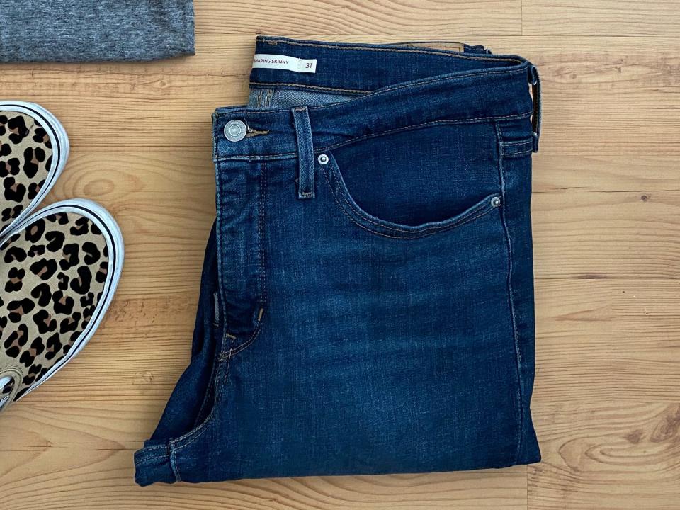 gray T-shirt, blue jeans, and leopard slip-on shoes on a hardwood floor