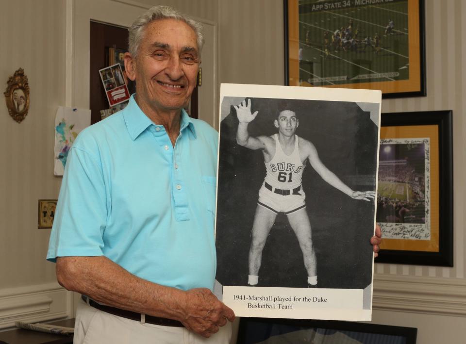 Former Duke basketball player Marshall Rauch poses with a photos from his time with Duke at his office on Union Road Friday afternoon. PHOTO MIKE HENSDILL/THE GAZETTE