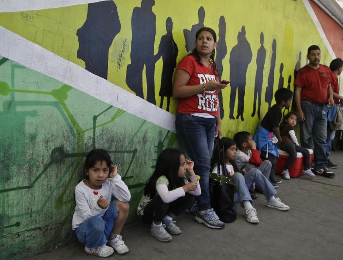 Sandra Ramirez stands with four of here children along the walkway to enter the United States where they came to support members of the group Border Dreamers and other supporters of an open border policy Monday, March 10, 2014, in Tijuana, Mexico. Ramirez said her family is in the United States as is the father fo her children. (AP Photo/Lenny Ignelzi)