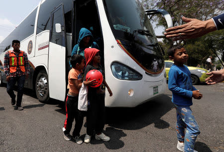 A Mexican police officer gestures as migrants from Honduras get off the bus, part of a caravan of Central American migrants moving through Mexico toward the U.S. border, in Puebla, Mexico April 6, 2018. REUTERS/Henry Romero