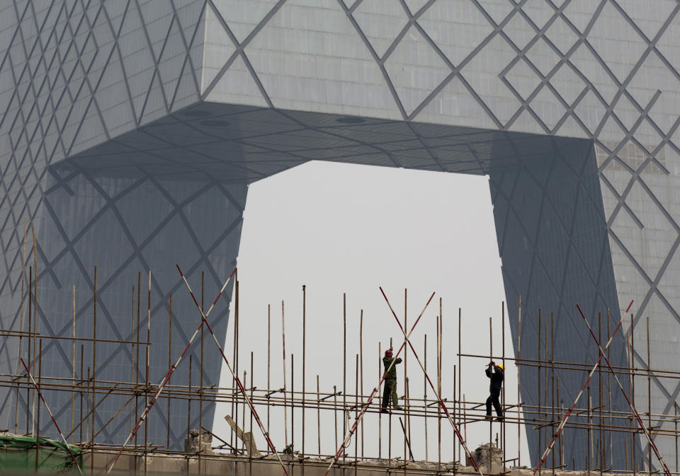FILE - In this Wednesday, April 2, 2014, file photo, workers install scaffolding on a construction site against the China Central Television building in Beijing. Economists fear a lending bubble in China could threaten the global economy unless the Chinese government shores up its financial system, according to an Associated Press survey. (AP Photo/Andy Wong, File)