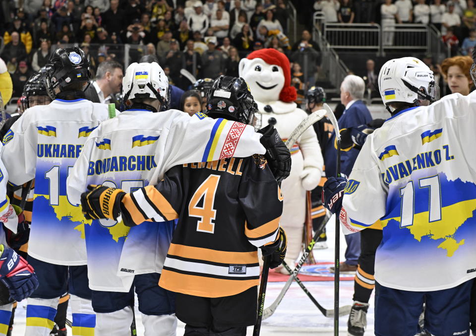 Ukraine and Boston Junior Bruins peewee team players stand together before a hockey game, Saturday, Feb, 11, 2023, in Quebec City. From left, Maksym Kukharenko, Oleksii Bondarchuk, Patrick Fennell and Zahar Kovalenko.(Jacques Boissinot/The Canadian Press via AP)