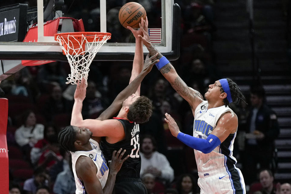 Houston Rockets center Alperen Sengun, center, shoots as Orlando Magic forward Paolo Banchero, right, and center Mo Bamba defend during the first half of an NBA basketball game Wednesday, Dec. 21, 2022, in Houston. (AP Photo/Eric Christian Smith)