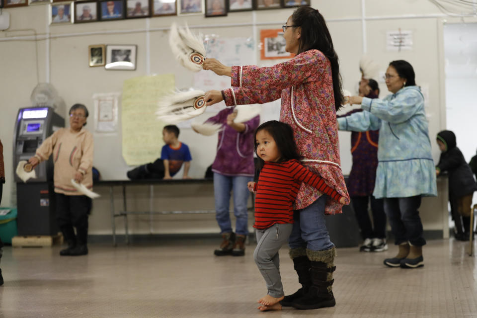 In this Monday, Jan. 20, 2020 photo, Liana Nicholai clings to her grandmother, Dora Nicholai, during an Alaska Native dance in Toksook Bay, Alaska, a mostly Yup'ik village on the edge of the Bering Sea. Census workers traditionally begin the official decennial count in rural Alaska when the ground is still frozen. That allows easier access before the spring melt makes many areas inaccessible to travel and residents scatter to subsistence hunting and fishing grounds. The rest of the nation, including more urban areas of Alaska, begin the census in mid-March. (AP Photo/Gregory Bull)