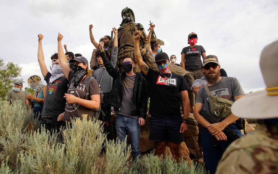 Demonstrators climb the statue of Don Juan de Onate in Old Town in Albuquerque - The Albuquerque Journal 