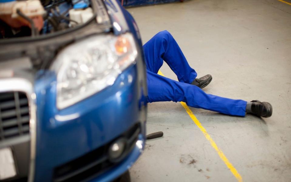 car mechanic working underneath - only his legs visible - Media Mogul/Rex Features