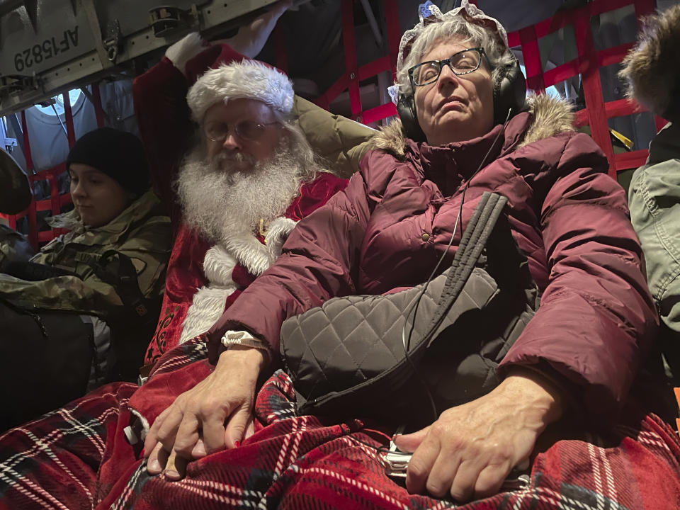 Santa and Mrs Claus rest on the plane trip to Nuiqsut, Alaska, on Tuesday, Nov. 29, 2022. Operation Santa Claus, the Alaska National Guard's outreach program, attempts to bring Santa and Mrs. Claus and gifts to children in two or three Alaska Native villages each year. (AP Photo/Mark Thiessen)