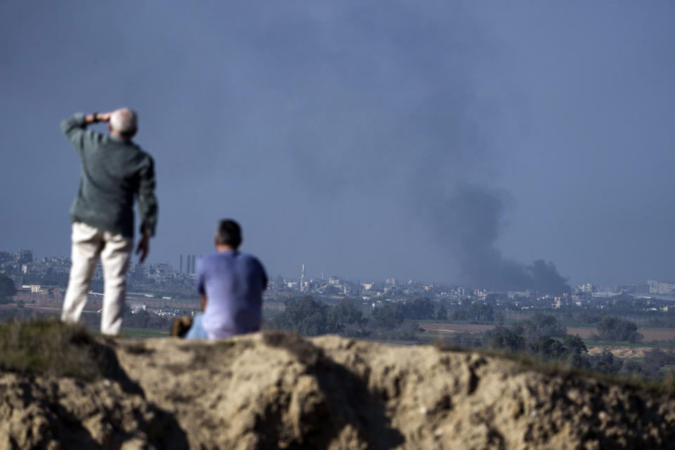 People watch smoke rising to the sky after an explosion in the Gaza Strip, as seen from southern Israel, Saturday, Jan. 6, 2024. In Gaza, Israel is moving to scale down its military assault in the north of the territory and pressing its heavy offensive in the south, vowing to crush Hamas. (AP Photo/Leo Correa)