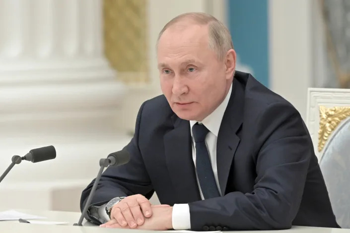 Russia's President Vladimir Putin, hands folded and with a half-smile, sits on a gilt-encrusted chair in the Kremlin and leans into microphone.