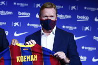 Ronald Koeman holds up a soccer shirt with his name on it during his official presentation as coach for FC Barcelona in Barcelona, Spain, Wednesday, Aug. 19, 2020. Barcelona officially announced earlier on Wednesday a deal with Koeman to become their coach five days after the team's humiliating 8-2 loss to Bayern Munich in the Champions League quarterfinals. Barcelona says the former defender's deal runs through June 2022. Koeman replaces the fired Quique Setien. (AP Photo/Joan Monfort)