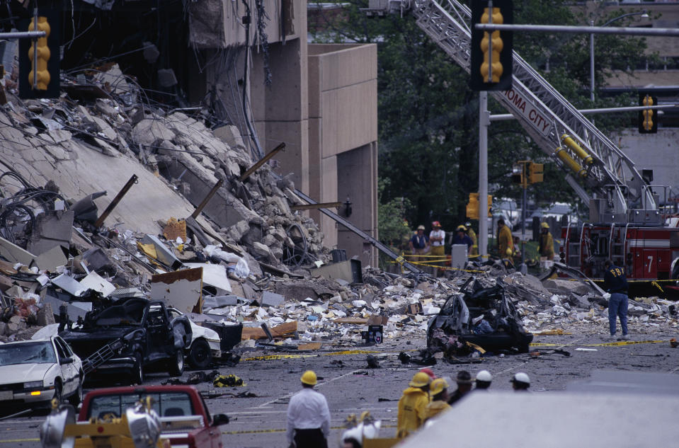 Rescue workers and emergency personnel respond to a scene of building rubble and destroyed cars amid the aftermath of an incident in an urban area